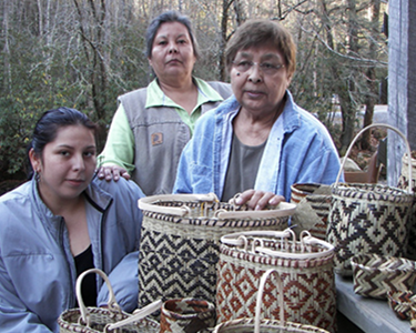 Three Native American women with handmade baskets.