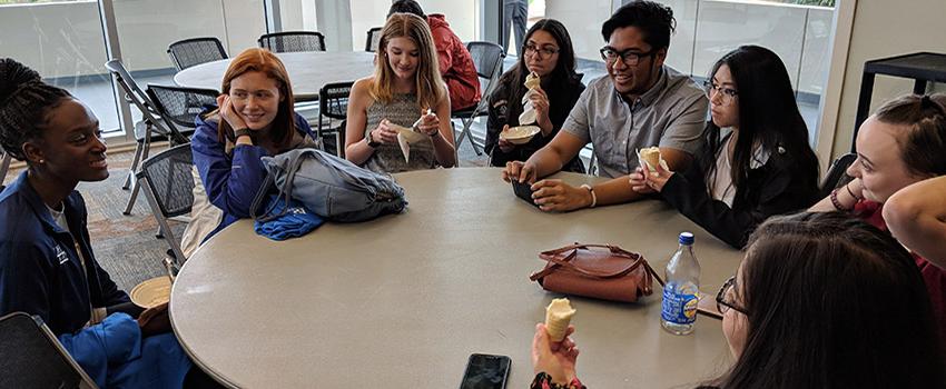 Honors students sitting around table in Student Center talking and eating ice cream