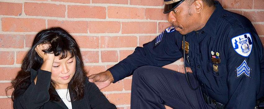 Police Officer helping a woman sitting on the floor